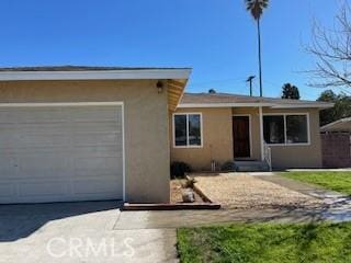 ranch-style house with concrete driveway, an attached garage, and stucco siding