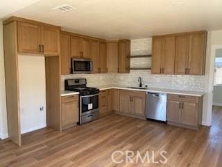 kitchen with wood finished floors, light countertops, appliances with stainless steel finishes, and a sink