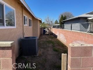 view of home's exterior with central air condition unit, fence, and stucco siding