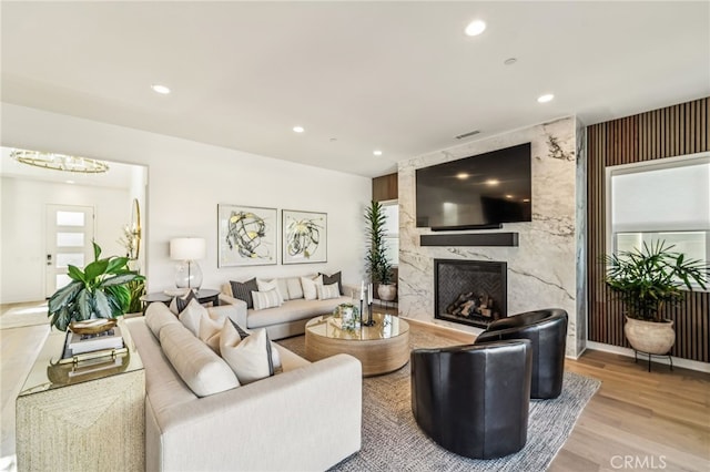 living room featuring a high end fireplace, recessed lighting, and wood finished floors