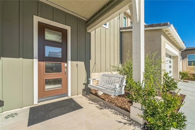 view of exterior entry featuring covered porch and board and batten siding