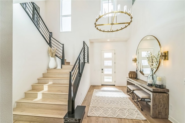 entryway with stairs, a high ceiling, wood finished floors, and a healthy amount of sunlight