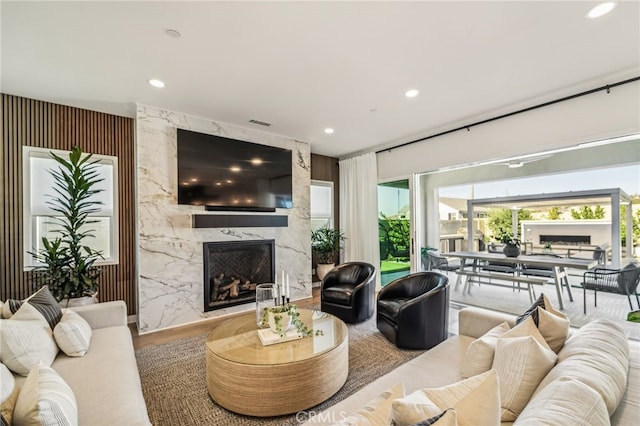 living room with recessed lighting, visible vents, wood finished floors, and a high end fireplace