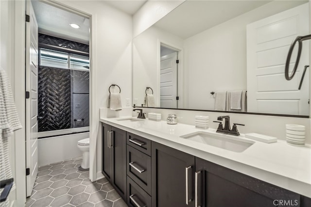 full bathroom with toilet, double vanity, a sink, and tile patterned floors