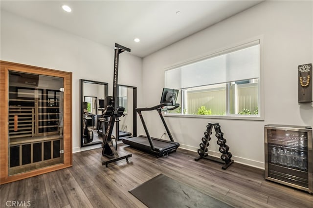 exercise room with recessed lighting, beverage cooler, baseboards, and wood finished floors