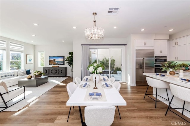 dining area with light wood finished floors, visible vents, an inviting chandelier, and recessed lighting