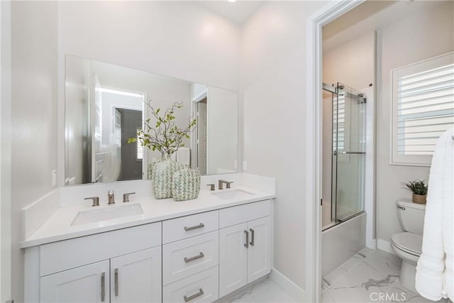 bathroom with toilet, marble finish floor, and a sink