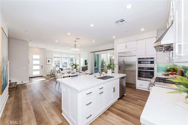 kitchen with light wood finished floors, visible vents, appliances with stainless steel finishes, light countertops, and a sink