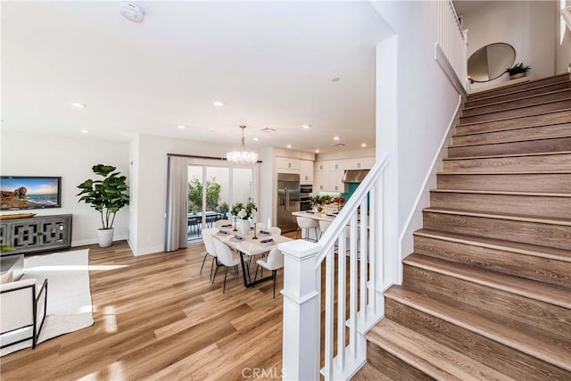 stairs featuring baseboards, an inviting chandelier, wood finished floors, and recessed lighting