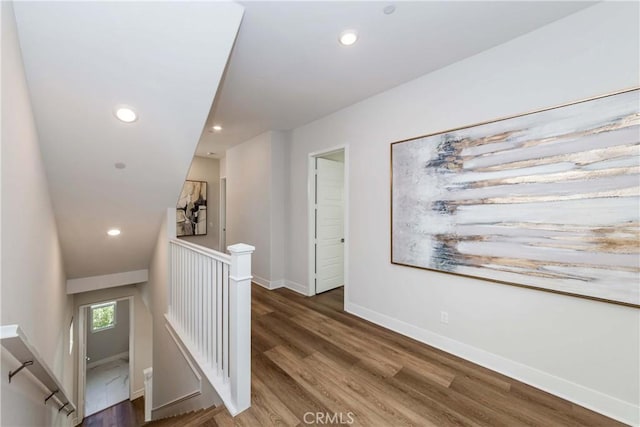 hallway with recessed lighting, baseboards, an upstairs landing, and wood finished floors