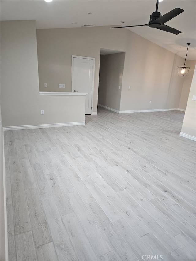 spare room featuring lofted ceiling, light wood finished floors, a ceiling fan, and baseboards