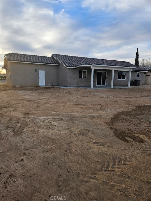 rear view of property featuring a tile roof and stucco siding