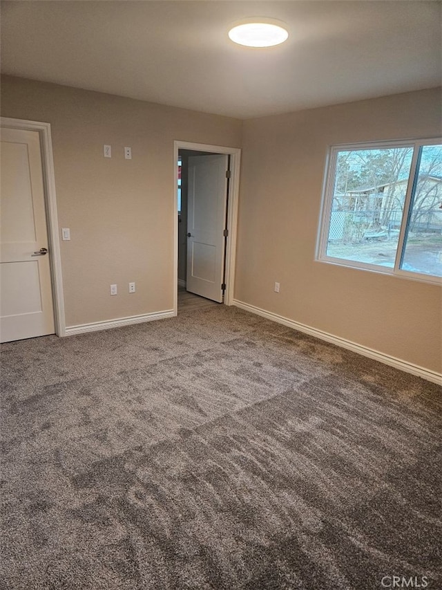 unfurnished room featuring carpet floors and baseboards