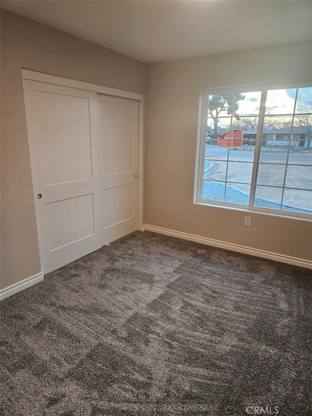 unfurnished bedroom featuring a closet, baseboards, and carpet flooring