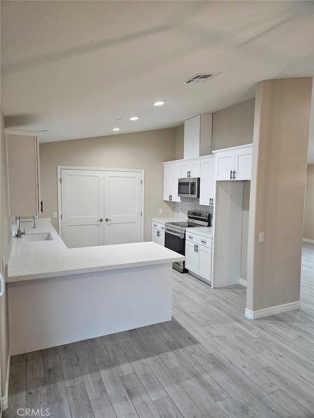 kitchen with light wood-style floors, tasteful backsplash, appliances with stainless steel finishes, and white cabinets