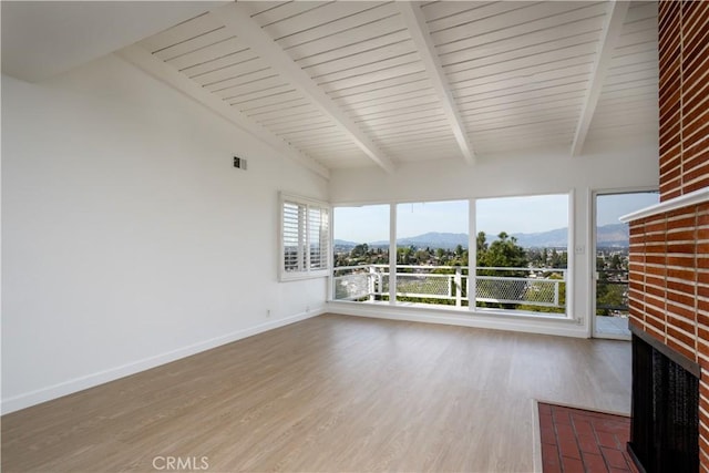 unfurnished sunroom with lofted ceiling with beams, a fireplace, and a mountain view