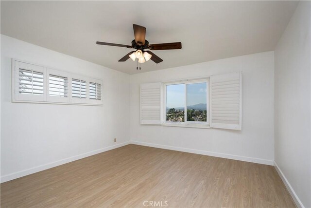 unfurnished room featuring light wood finished floors, a ceiling fan, and baseboards