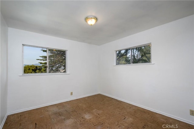 spare room with parquet floors and baseboards