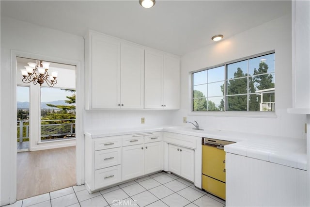 kitchen featuring dishwasher, a sink, a wealth of natural light, and white cabinets