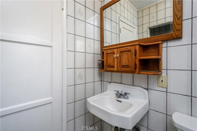 half bath featuring toilet, tile walls, and a sink