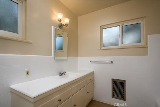 bathroom featuring a wainscoted wall, vanity, visible vents, and tile walls