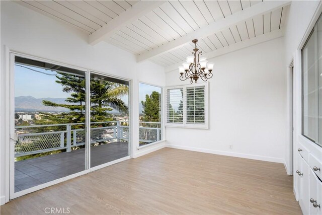 unfurnished sunroom featuring lofted ceiling with beams, wood ceiling, a chandelier, and a mountain view