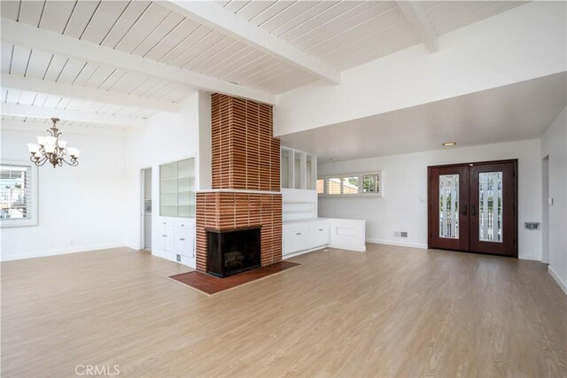 unfurnished living room with french doors, lofted ceiling with beams, a brick fireplace, wood finished floors, and baseboards