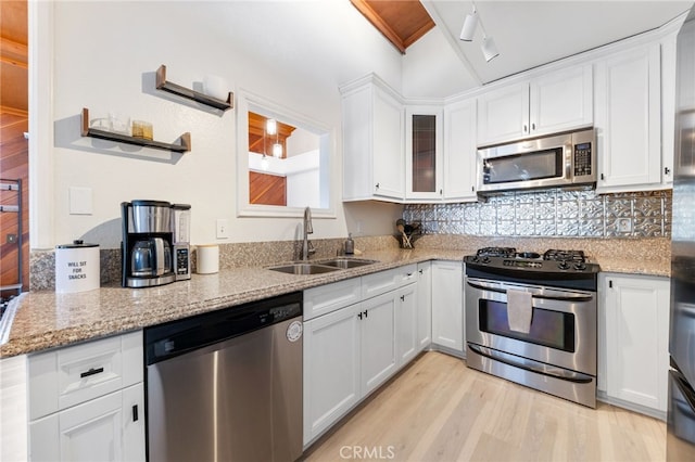 kitchen featuring light wood finished floors, stainless steel appliances, backsplash, white cabinetry, and a sink