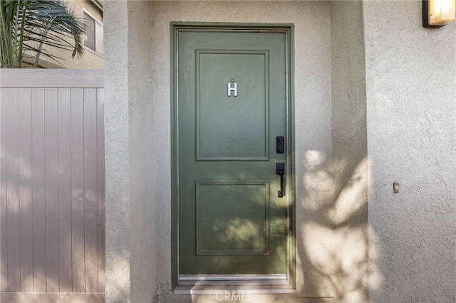 property entrance featuring fence and stucco siding