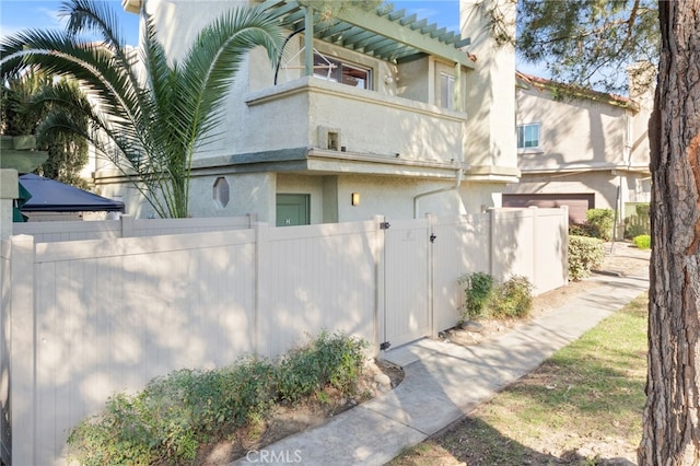 view of home's exterior featuring a fenced front yard, a balcony, and stucco siding