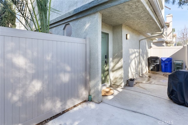 view of side of home with a patio area, fence, and stucco siding