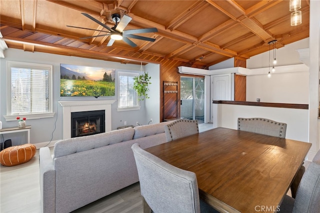 dining room featuring lofted ceiling with beams, a ceiling fan, wood finished floors, wooden ceiling, and a lit fireplace