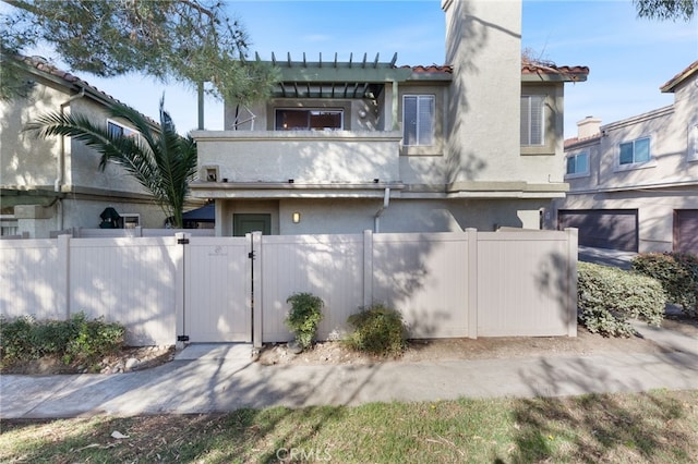 exterior space with a balcony, a fenced front yard, a gate, and stucco siding