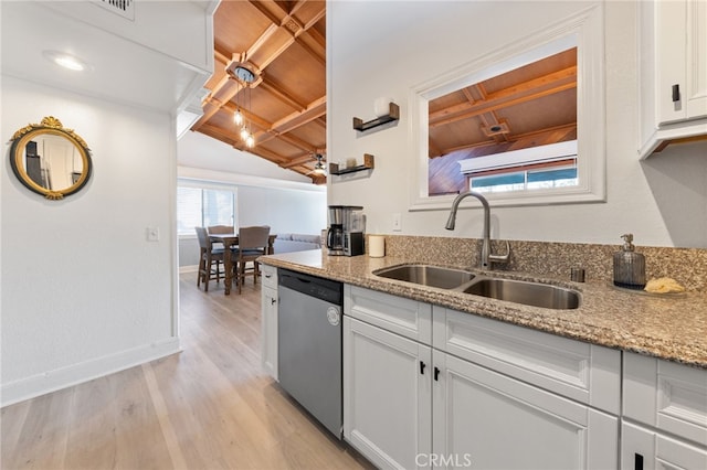 kitchen with light wood finished floors, white cabinets, light stone countertops, stainless steel dishwasher, and a sink