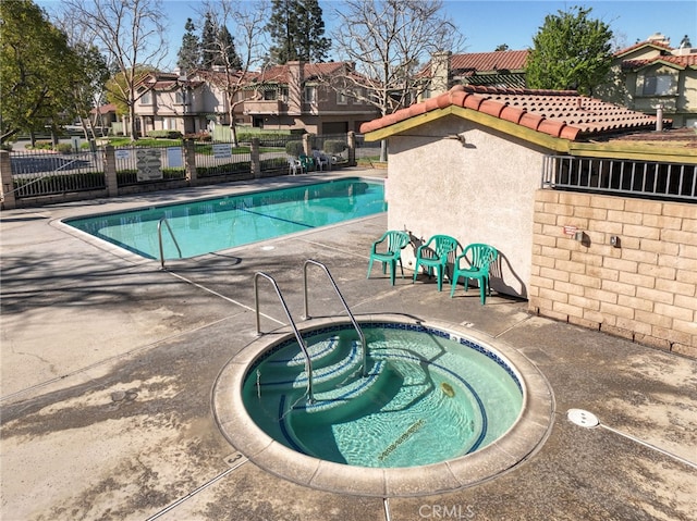 community pool with fence, a hot tub, and a patio