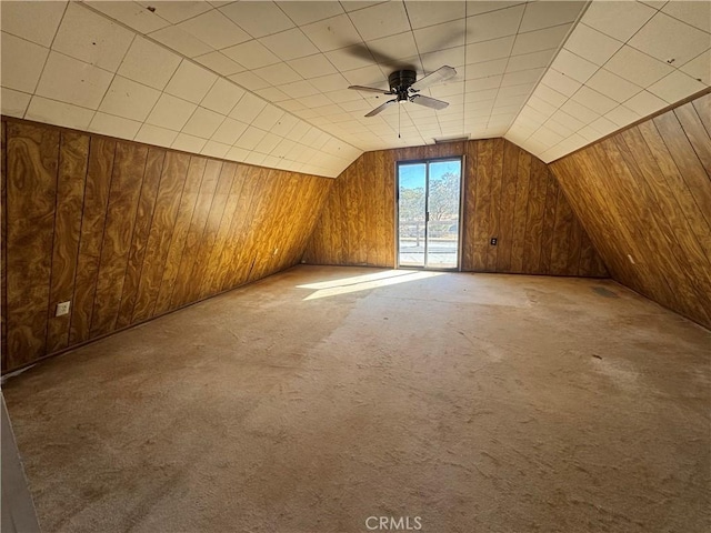 additional living space with wood walls, carpet, vaulted ceiling, and ceiling fan