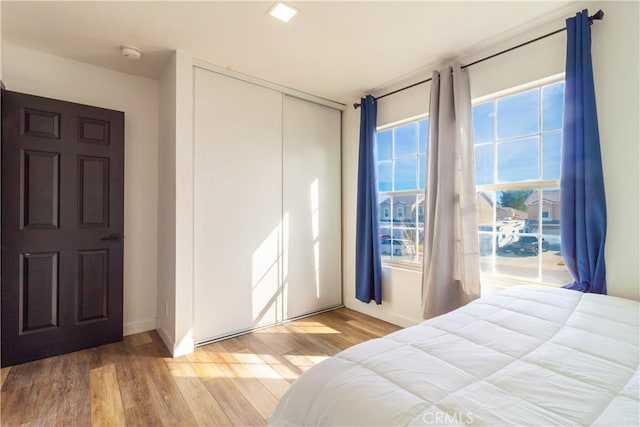 bedroom with a closet, baseboards, and wood finished floors