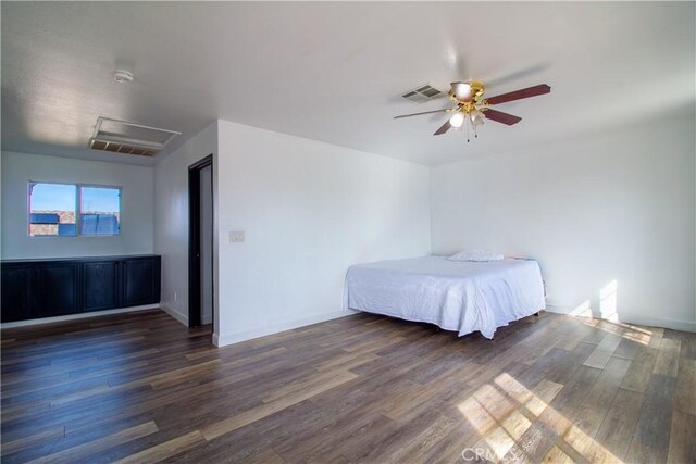 unfurnished bedroom with attic access, a ceiling fan, visible vents, and wood finished floors