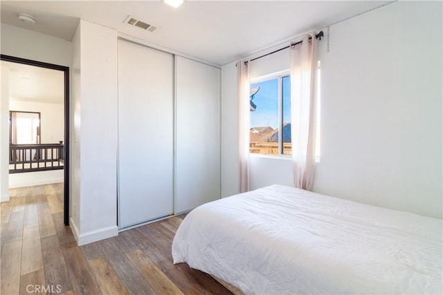 bedroom featuring multiple windows, wood-type flooring, a closet, and visible vents