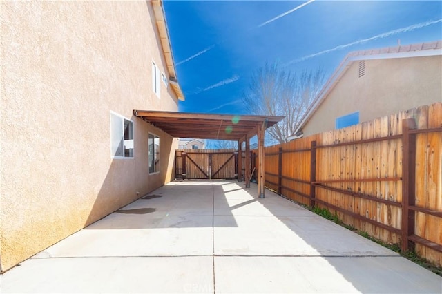 view of patio with driveway, a carport, fence, and a gate