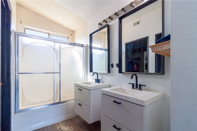 bathroom featuring vaulted ceiling, visible vents, a sink, and wood finished floors