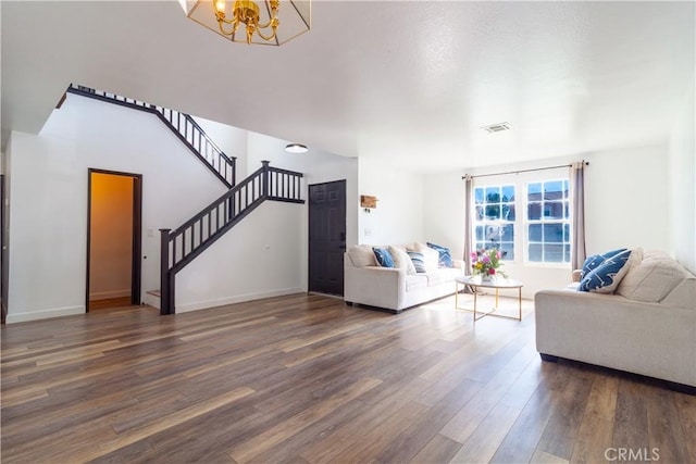 living room with a notable chandelier, wood finished floors, visible vents, baseboards, and stairs