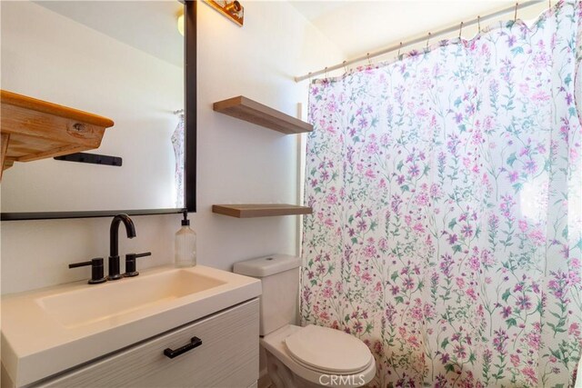 bathroom with toilet, a shower with shower curtain, and vanity