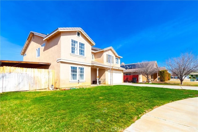 rear view of house with a lawn, concrete driveway, an attached garage, fence, and stucco siding