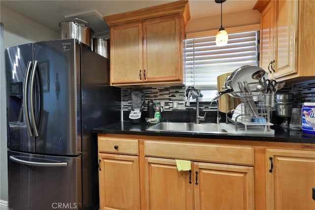 kitchen featuring a sink, hanging light fixtures, decorative backsplash, and black fridge