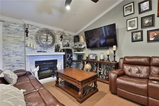 living room featuring lofted ceiling, ornamental molding, wood finished floors, and a glass covered fireplace