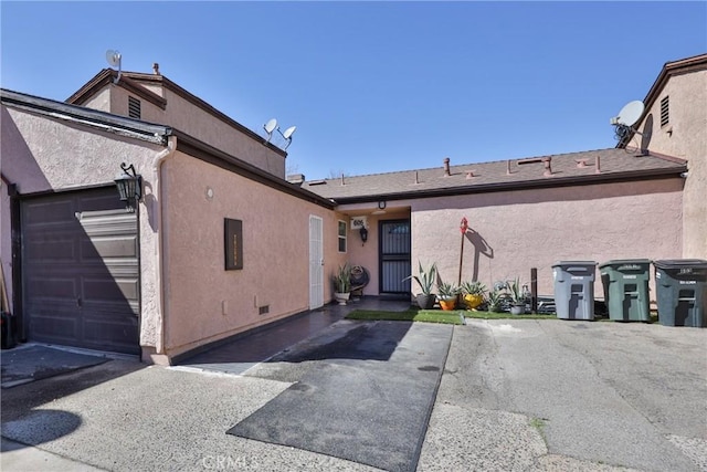 back of house featuring a garage and stucco siding