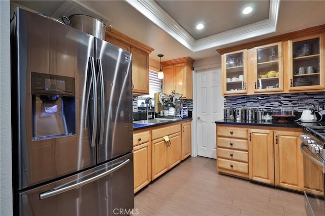 kitchen featuring crown molding, dark countertops, a raised ceiling, a sink, and stainless steel fridge with ice dispenser