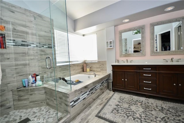 bathroom with a stall shower, double vanity, a sink, and a bath