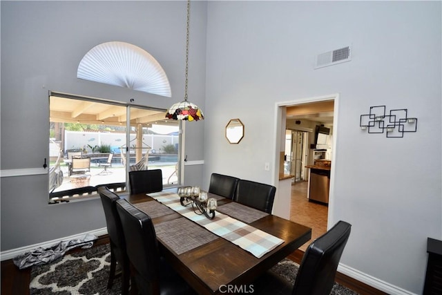 dining area with baseboards, a high ceiling, and visible vents